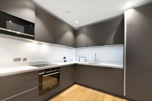 1 Bedroom Close to Tower Hill في لندن: مطبخ مع دواليب سوداء وبيضاء ومغسلة