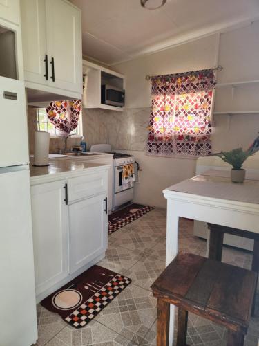 a kitchen with white cabinets and a table and a window at Valdu Cozy Cottage in Christ Church