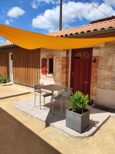żółty baldachim nad stołem i krzesłami na patio w obiekcie Studio de charme indépendant w mieście Belin-Beliet