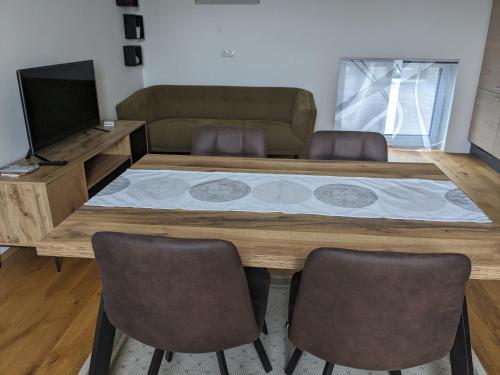 sala de estar con mesa con sillas y TV en Ferienwohnung Genusshaus TIMIschl, en Sankt Margarethen an der Raab