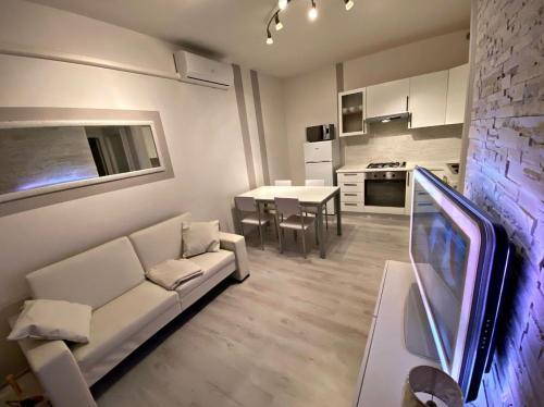 a living room with a white couch and a kitchen at [SolMare] Apartments - Private parking - Pool in Rosapineta