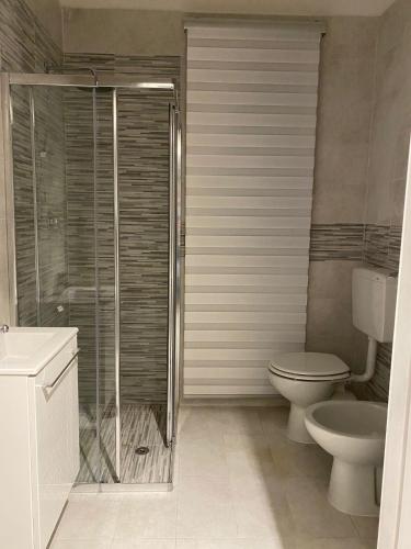a bathroom with a toilet and a glass shower at [SolMare] Apartments - Private parking - Pool in Rosapineta