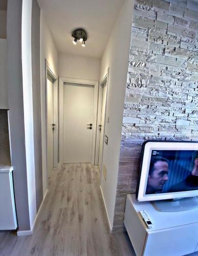 een woonkamer met een tv en een bakstenen muur bij [SolMare] Apartments - Private parking - Pool in Rosapineta