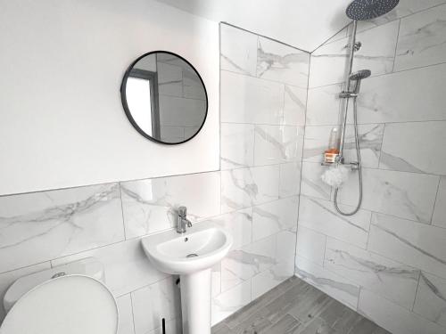 ein weißes Badezimmer mit einem Waschbecken und einem Spiegel in der Unterkunft 53 Church Street in Warrington