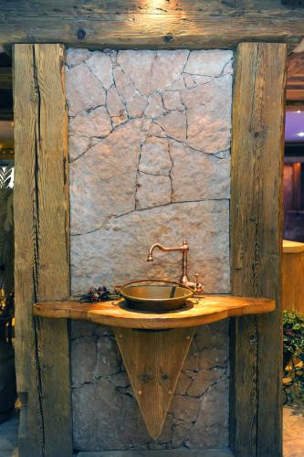 a wooden counter with a sink on a stone wall at Wellness Hotel Dolomia in Soraga