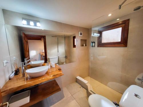a bathroom with two sinks and a toilet and a shower at Vuelvo al Sur Alojamiento Lago Puelo in Lago Puelo