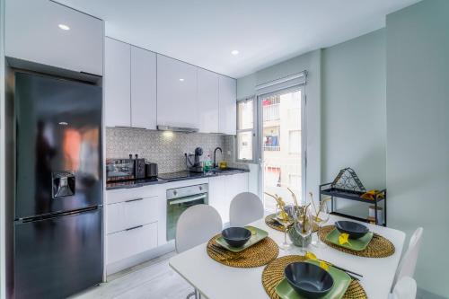 een keuken met een tafel, stoelen en een koelkast bij Palangre Beach Apartment in Torrevieja