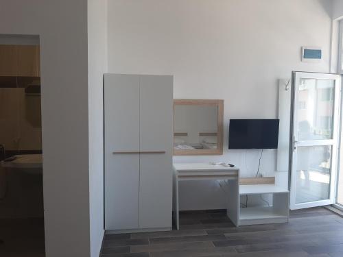 Habitación con escritorio blanco y TV. en Апартаменти Жени en Tsarevo