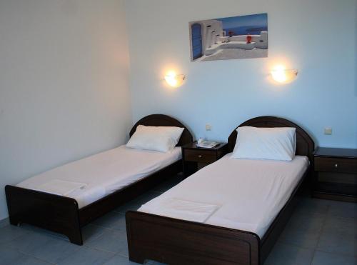 two beds in a room with two lamps on the wall at Studios Psiloritis in Lístaros