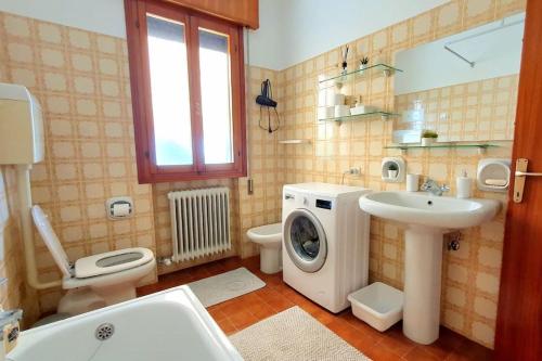 ein Badezimmer mit einer Waschmaschine und einem Waschbecken in der Unterkunft NIKO apartment in Santo Stino di Livenza