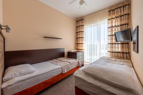 a hotel room with two beds and a tv at Albatros Spa & Ski in Jarosławiec