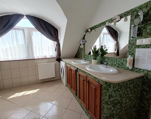 a bathroom with two sinks and two windows at Malom-tó Vendégház Tapolca in Tapolca