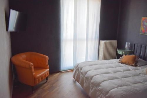 una camera con un letto e una sedia accanto a una finestra di Casa Macina a CastellʼAlfero