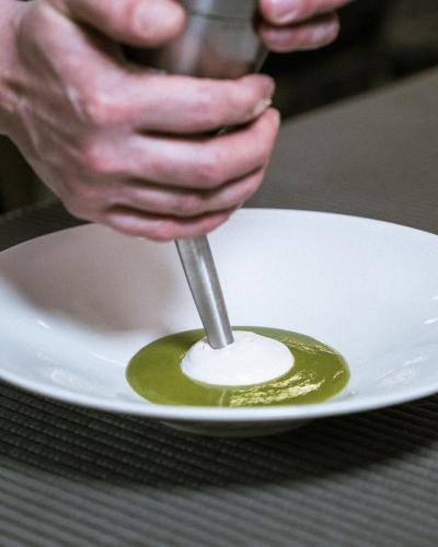 a person holding a spoon with green sauce on a plate at Il Castello Di San Gaudenzio in Cervesina