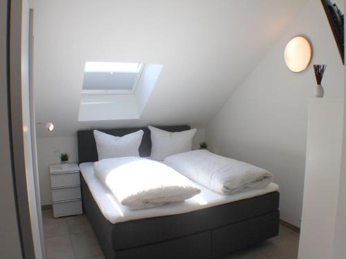 a small bedroom with a bed with white sheets and pillows at Sonnengarten 21 in Kellenhusen