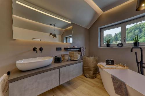La salle de bains est pourvue d'un grand lavabo blanc et d'une baignoire. dans l'établissement Chalet Panorama, à Freyung