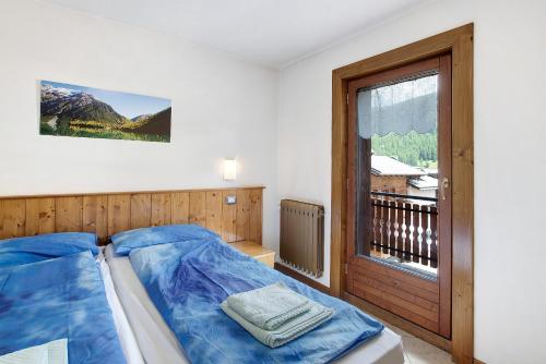 a bedroom with a blue bed and a window at Appartamento Bormetti Paolo Sara in Livigno