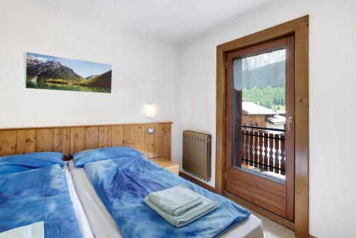 Un dormitorio con una cama azul y una ventana. en Appartamento Bormetti Paolo Sara, en Livigno