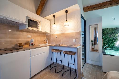 een keuken met witte kasten en barkrukken bij BALI ROOM / Magnifique studio évasion JACCUZI in Montgeron