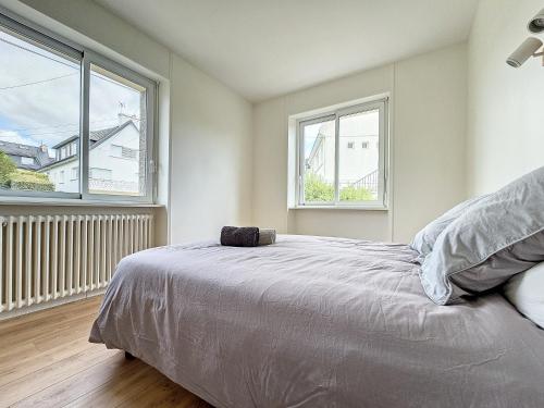 a bedroom with a bed and two windows at Minven in Concarneau