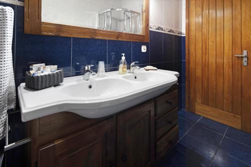 baño con lavabo blanco y azulejos azules en Casa das Rosas, en Angra do Heroísmo