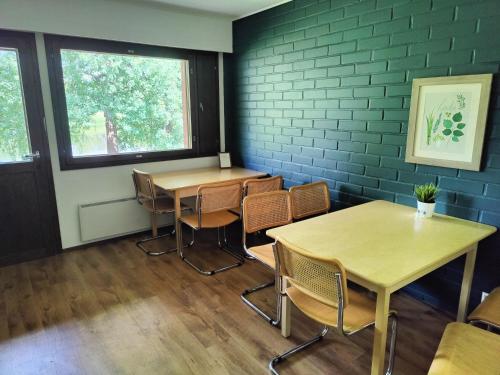 two tables and chairs in a room with a brick wall at Jokirannan Majoitus in Kokemäki