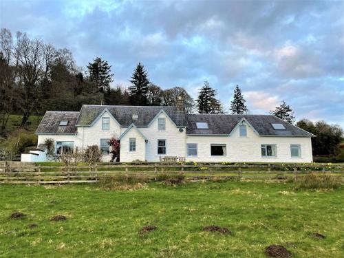 a large white house with a fence in a field at Kenmure Kennels in New Galloway