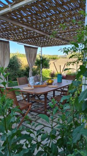 een houten tafel en stoelen onder een pergola bij Bio&B Acquaviva in Otranto