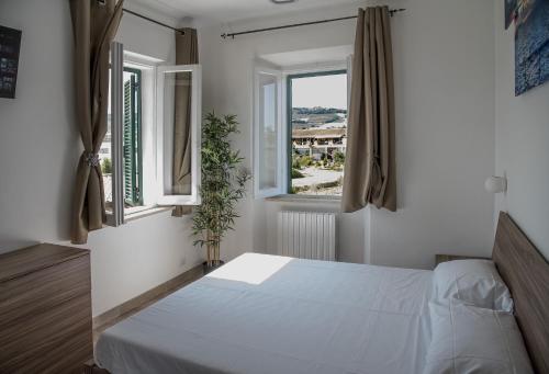 a bedroom with a white bed and two windows at QUEEN appartamenti e camere in Campofilone