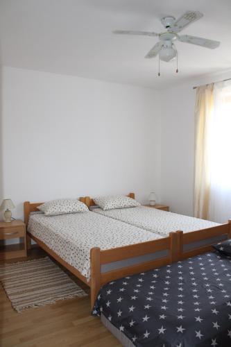 a bedroom with two beds and a ceiling fan at Apartment Noel in Sveti Vid-Miholjice