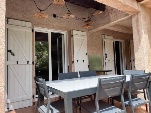 une salle à manger avec une table et des chaises blanches dans l'établissement Appartement avec piscine privée 4 à 6p 5min de la plage, à La Garonnette-Plage