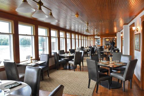 a dining room with tables and chairs and windows at Chestnut Inn at Oquaga Lake in Deposit