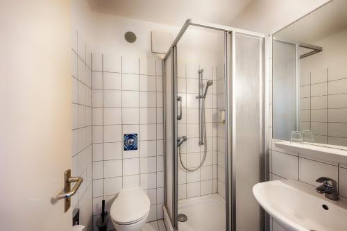 uma casa de banho com um chuveiro, um WC e um lavatório. em Enjoy Hotel am Studio em Berlim