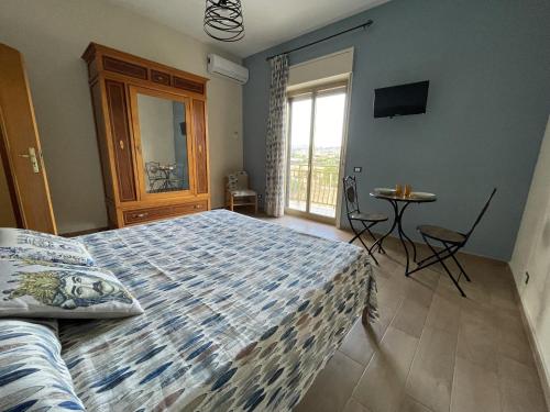 a bedroom with a bed and a table and a window at Namastè Apartments Agrigento in Agrigento