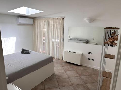 una camera bianca con un letto e una finestra di Villa Belvedere Versilia - Villa con tre camere, cucina, sala, giardino con piscina e vista - 7 posti letto a Camaiore