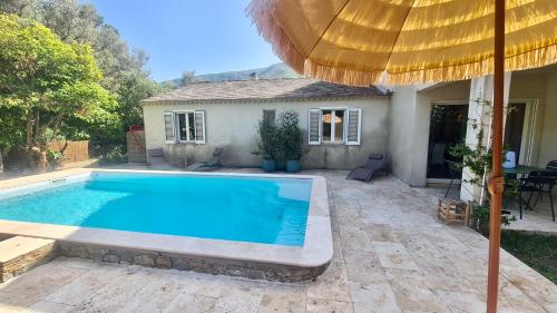 uma piscina em frente a uma casa com um guarda-chuva em Villa Murati 6 pers à 5 min de la mer em Sisco