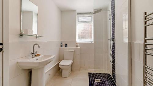 uma casa de banho branca com um lavatório e um WC em Beechwood House em The Mumbles