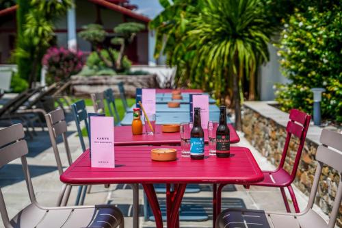 a red table with two bottles of beer on it at Hôtel Argia in Hasparren