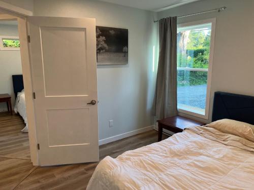 a bedroom with a door and a bed and a window at Kwalikum Kottage in Qualicum Beach