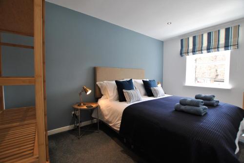 a bedroom with a bed with blue walls and a window at Murrays Neuk- stylish coastal apartment in Anstruther