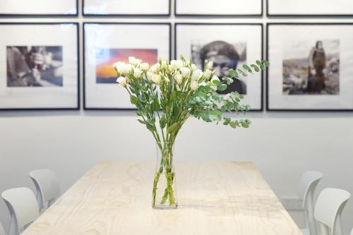 a vase of white flowers on a table with pictures at Travel of Swan International Hostel in Zhangjiajie
