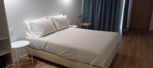 1 dormitorio con 1 cama con sábanas y almohadas blancas en Apartamentos Naturalis en Vila Nova de Milfontes