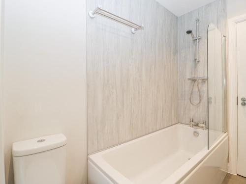 a white bathroom with a tub and a toilet at 2 The Old School in Cinderford