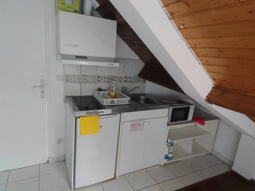 une petite cuisine avec des appareils blancs et un escalier dans l'établissement KL1-Bel Appart ds pavillon calme, à Montfermeil