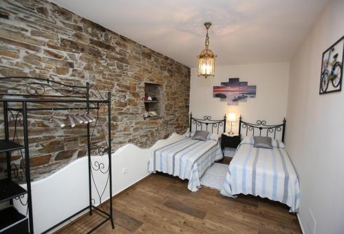 a bedroom with two beds and a brick wall at Apartamentos Rurales San Xillao in Ribadeo