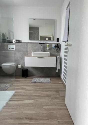 a bathroom with a sink and a toilet and a mirror at Hotel Papenbreer in Verl