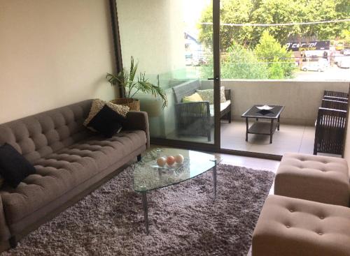 a living room with a couch and a glass table at Departamento ubicado en el corazón de Las Condes. in Santiago