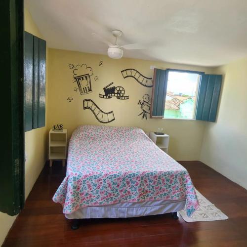 a bedroom with a bed and some drawings on the wall at Vila Barroca Estalagem in São Cristóvão
