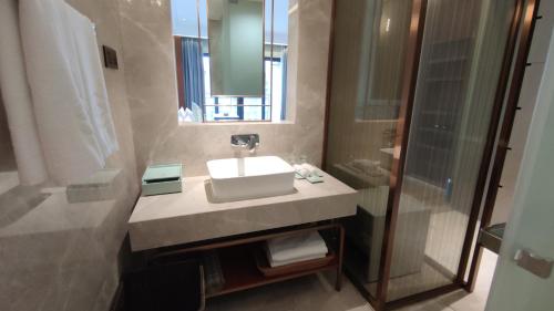 uma casa de banho com um lavatório e um chuveiro em Zhongzhou International Apartment em Sanya