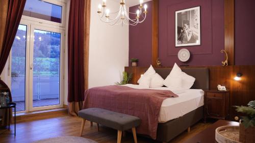 Schlafzimmer mit einem Bett, einem Fenster und einem Kronleuchter in der Unterkunft Vegan Hotel und Restaurants Nicolay 1881 in Zeltingen-Rachtig